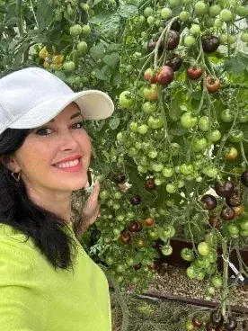 Елена Неграш рядом с кистями томатов